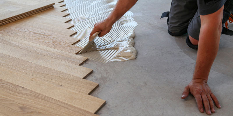 A man installing glue down vinyl tile flooring