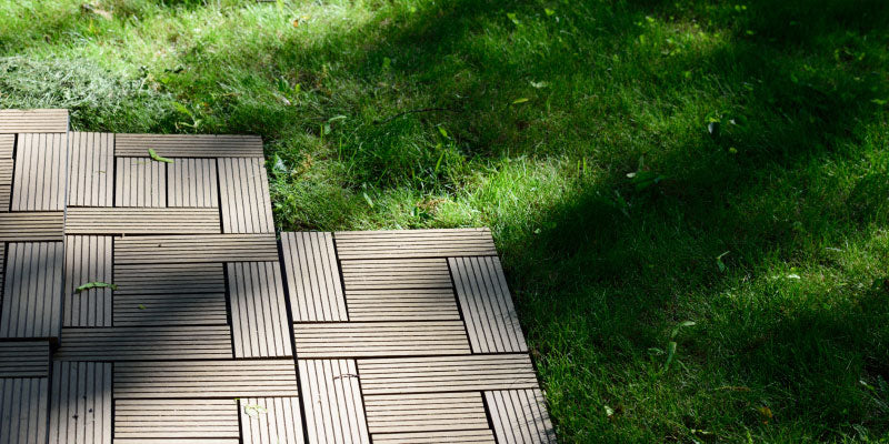 wooden deck tiles being installed over grass