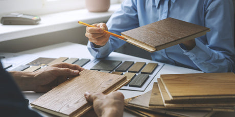 Image of two people working on a wood flooring project, illustrating the contrasting features of solid wood and engineered hardwood.