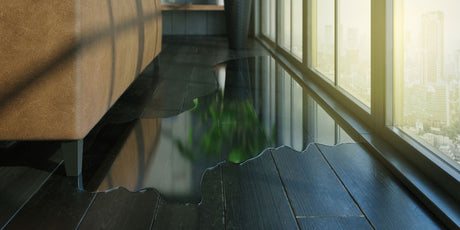 Water spilled over a hardwood flooring, causing possible damages.