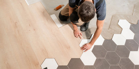 Image of a man laying tile over vinyl flooring