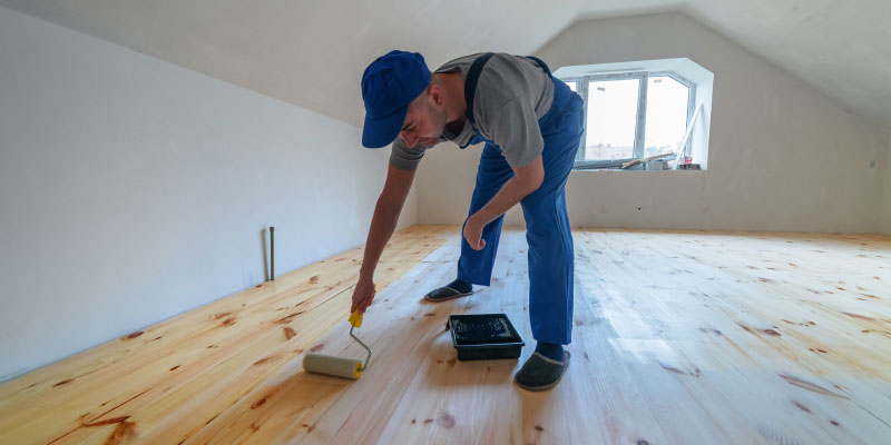 A man finishing a wood floor with an oil sealer