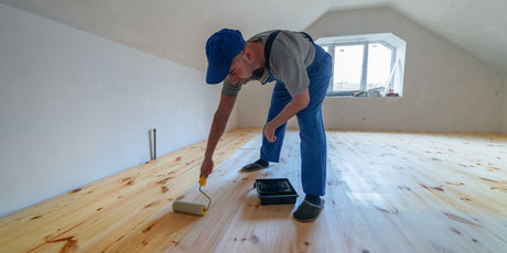 A man finishing a wood floor with an oil sealer