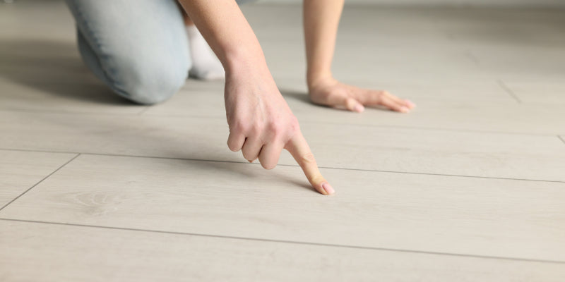 A person inspecting a floor for issues, Guide on addressing vinyl flooring problems.