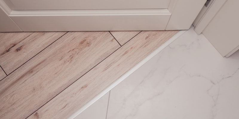 Example of flooring transition strips: vinyl floor and white tile.